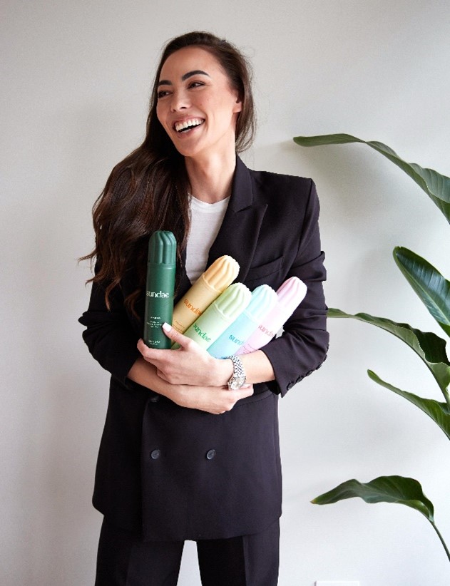 Co-Founder, Lizzie Waley photographed in this image smiling and holding a bunch of her products in her hands