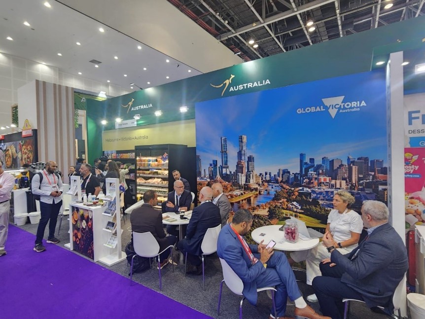 The Global Victoria trade stand at Gulfood 2025. People sit at tables discussing business whilst companies exhibit and showcase their products