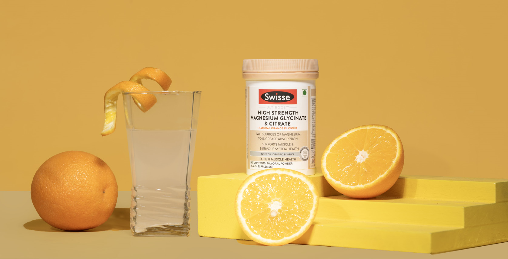 A display of Swisse products with a glass of water and oranges set next to the product